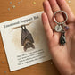 Keychain with a bat providing emotional support and a card with a message